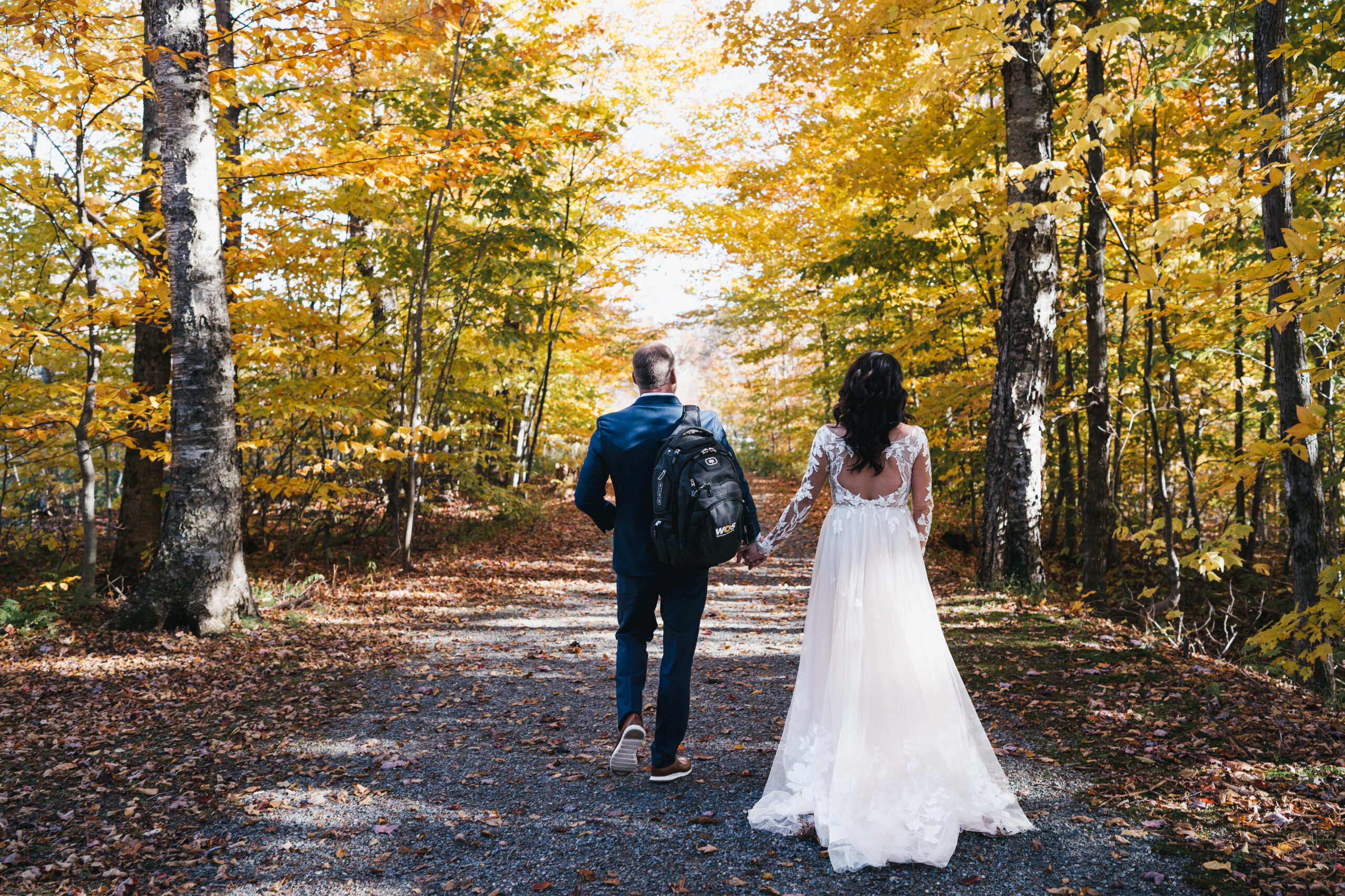 Bride and groom walking along the path enjoying the Fall foliage.