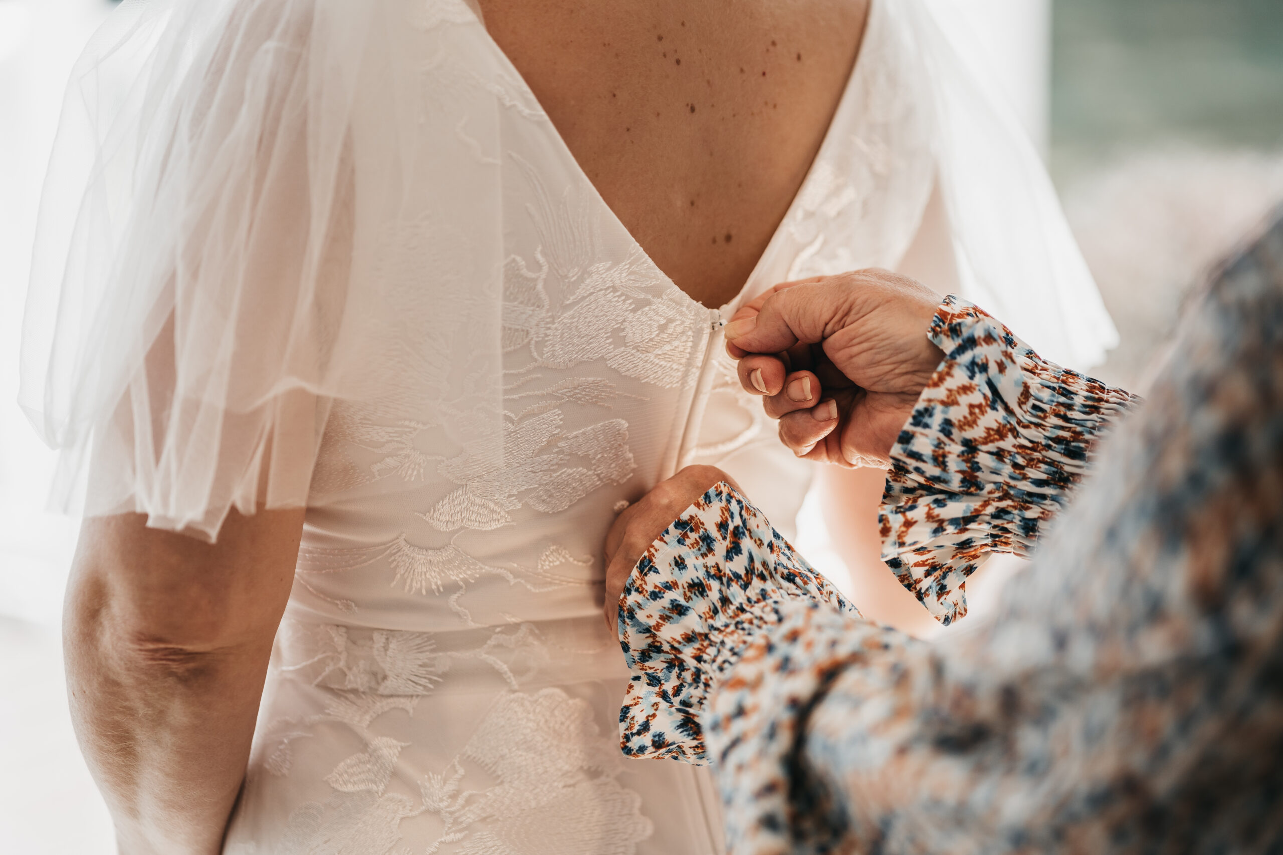 Mother helping bride into her dress during an intimate Michigan wedding.