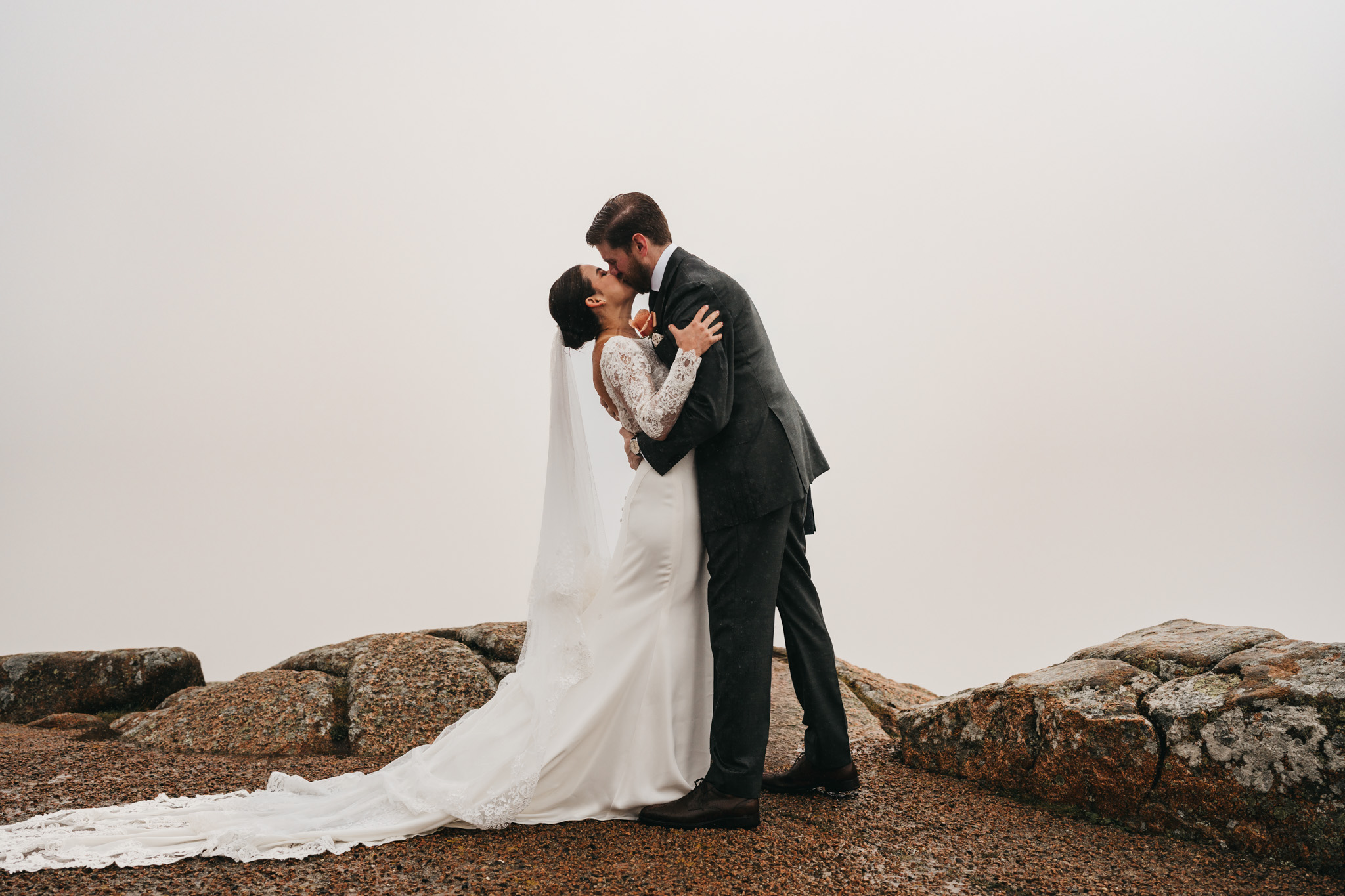 Bride and groom share their first kiss on Cadillac Mountain in Acadia National Park