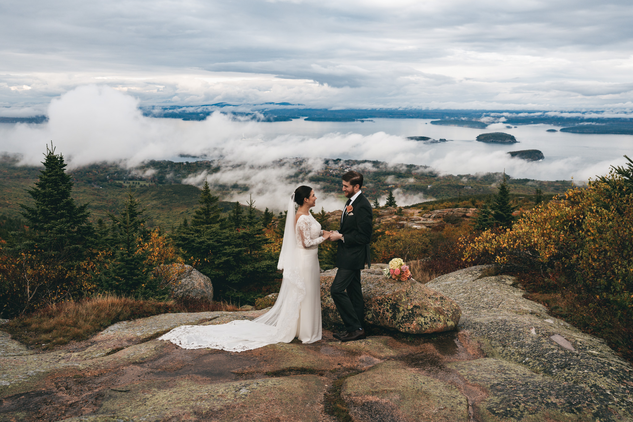 Bride and groom portraits in Acadia National Park with clouds rolling through the mountains