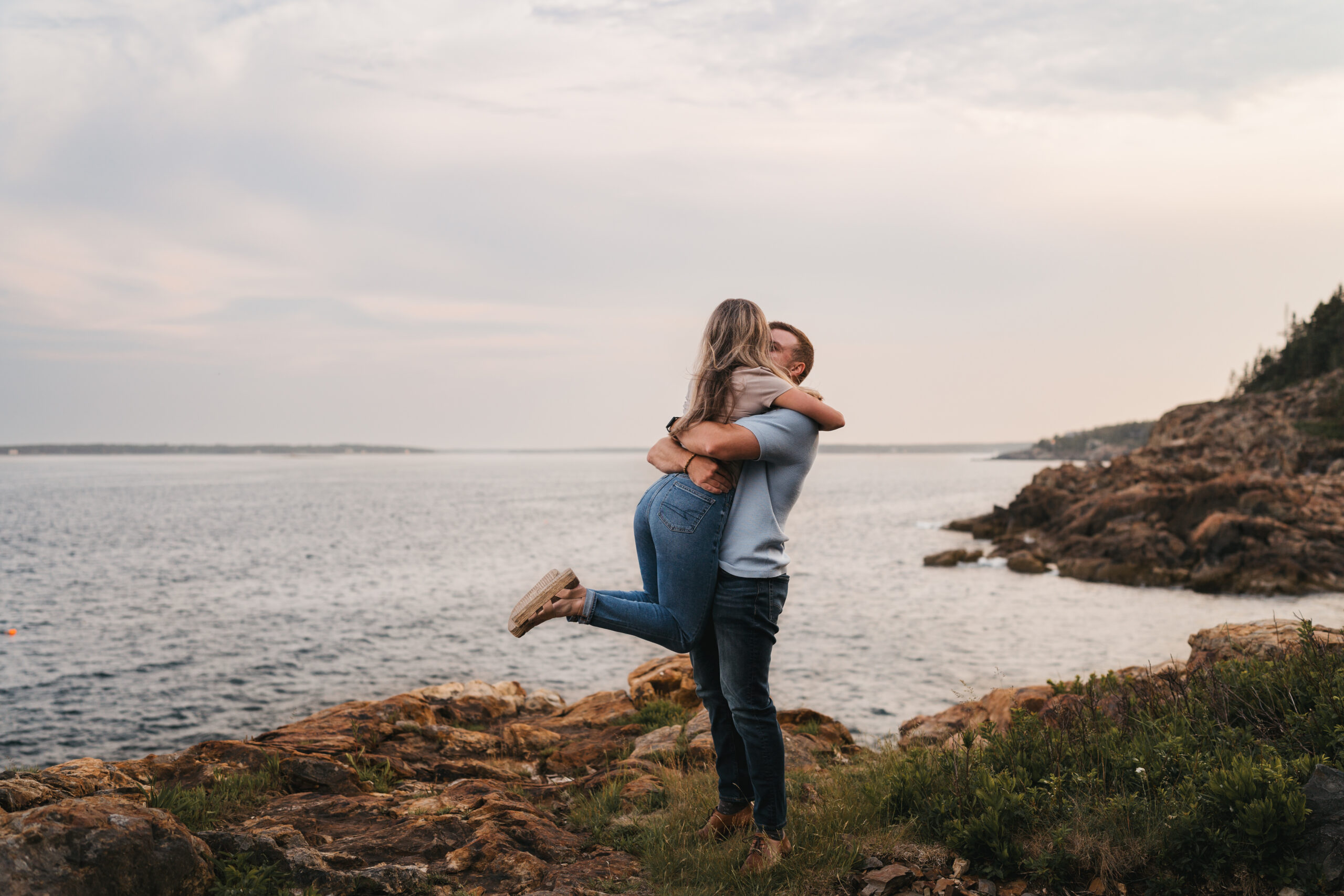Newly engaged couple celebrating during sunset proposal in Acadia