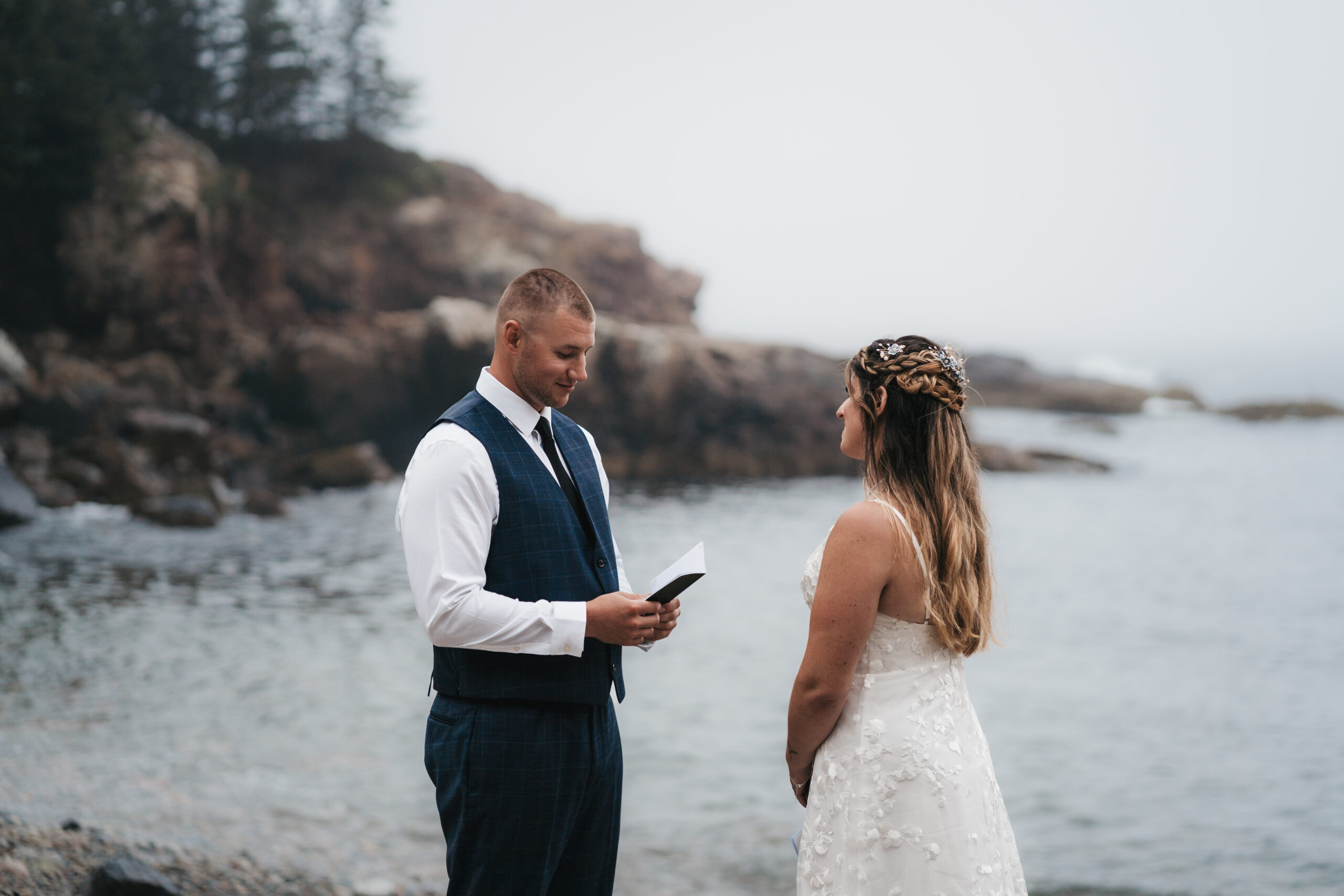 Couple exchanging vows on the pebble shore during their Maine Coastal elopement in Acadia National Park.