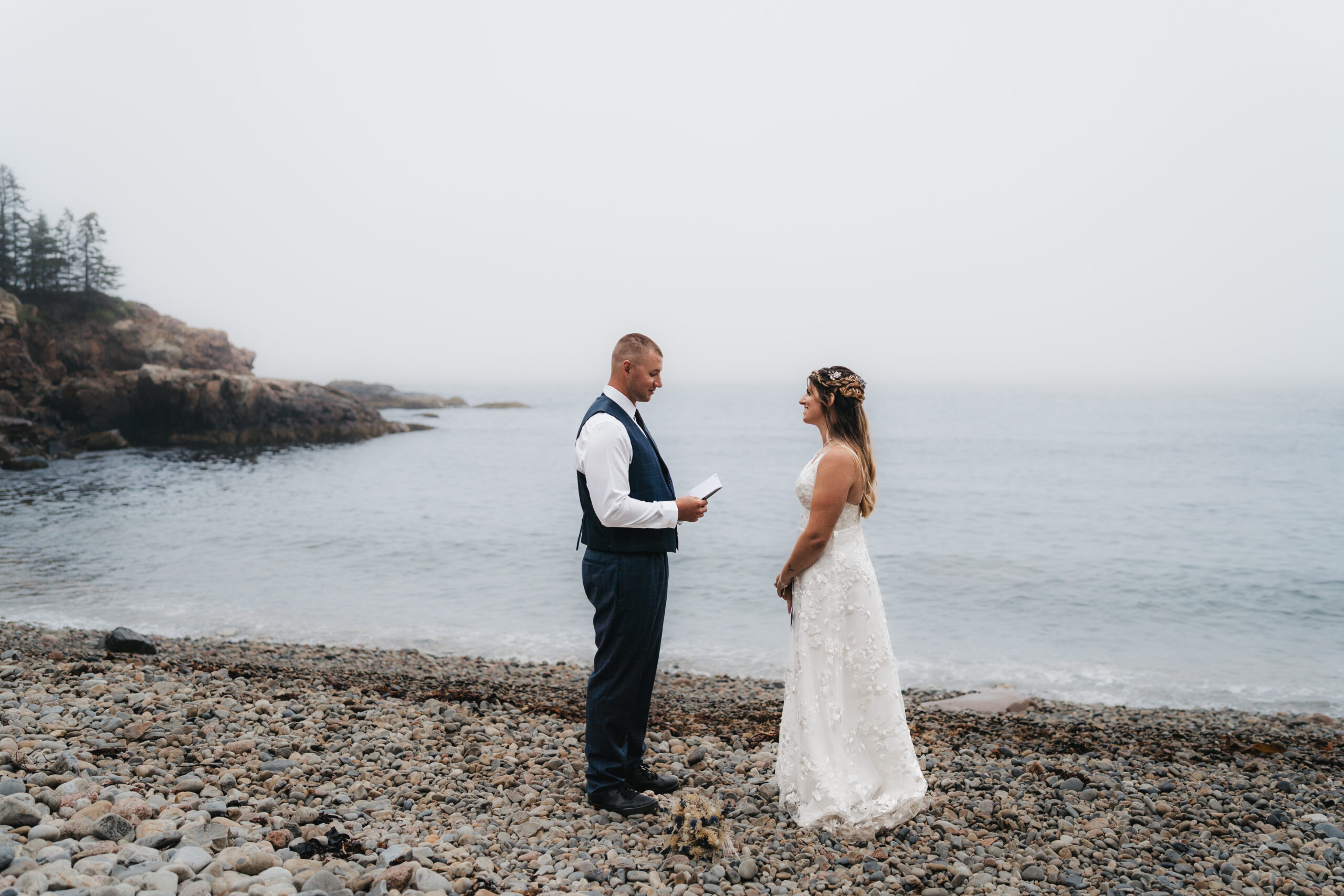 Couple exchanging vows on the pebble shores of Acadia.