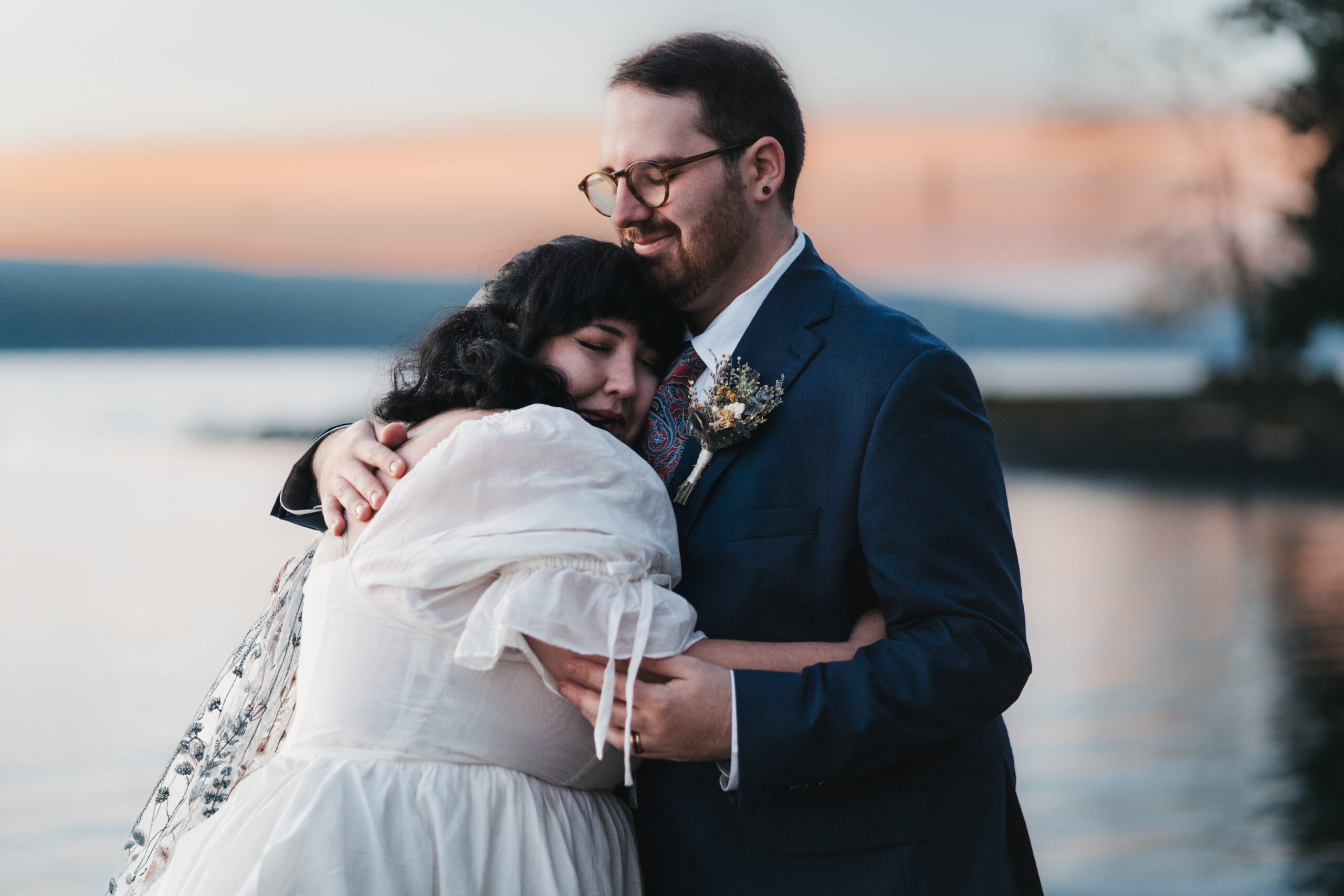Newlyweds embracing on a dock overlooking Seneca Lake during their Watkins Glen elopement.