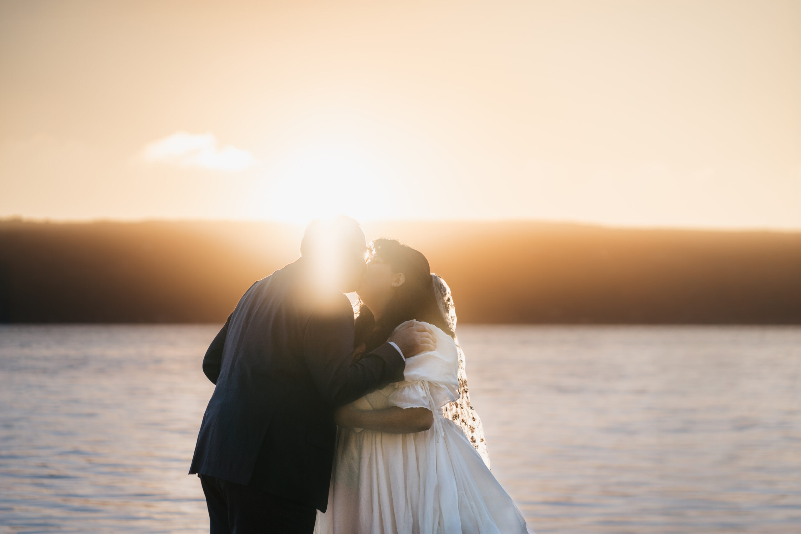 Bride and groom sharing first kiss during a sunrise Watkins Glen elopement.