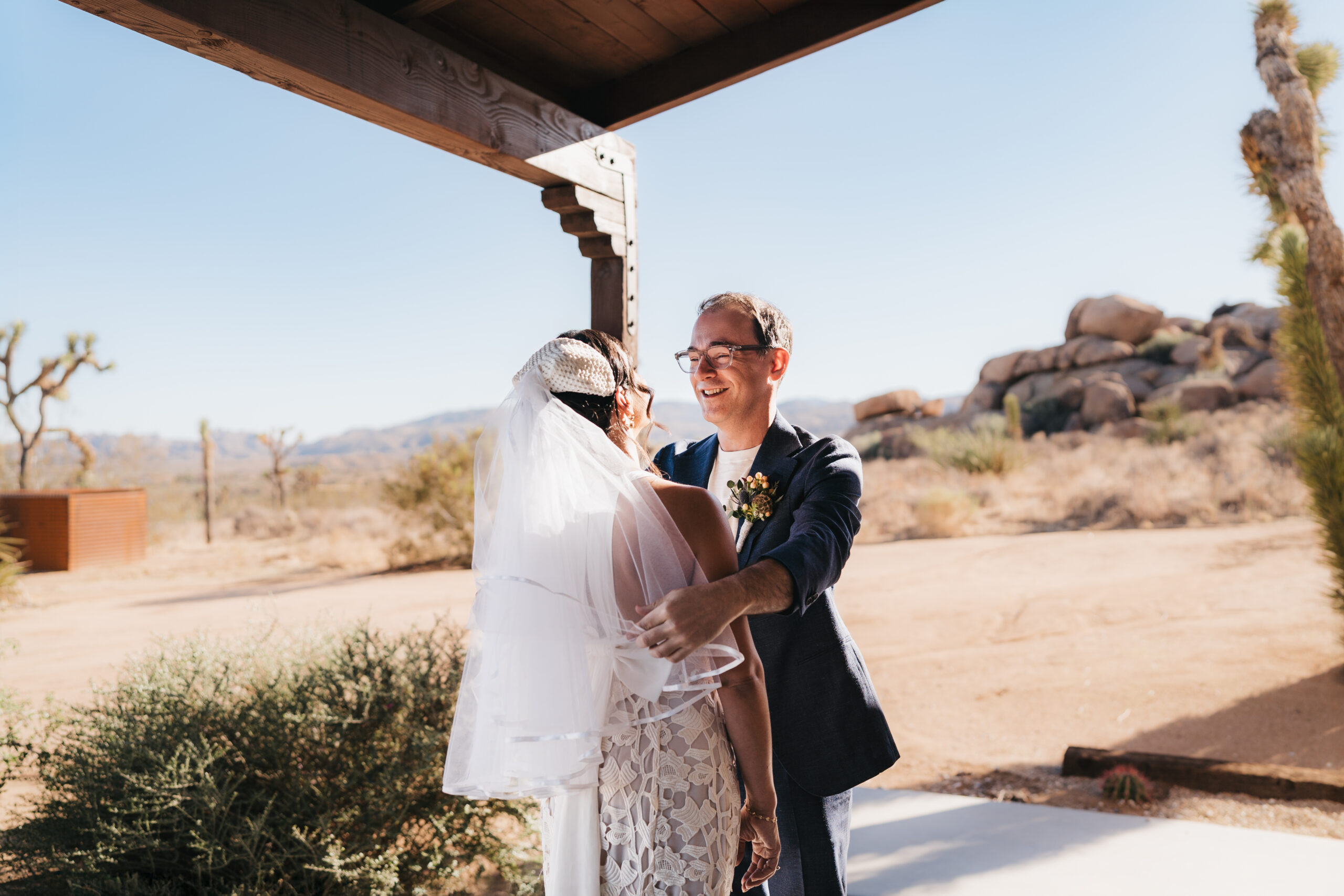 Groom lifting bride’s veil during an intimate Joshua Tree elopement.
