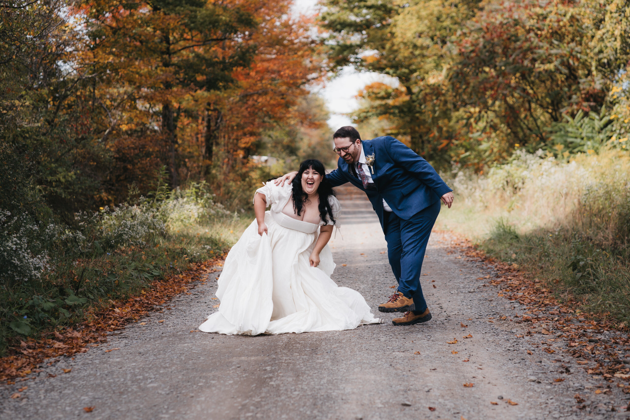 Bride and groom laughing together on scenic fall road during a Watkins Glen elopement.
