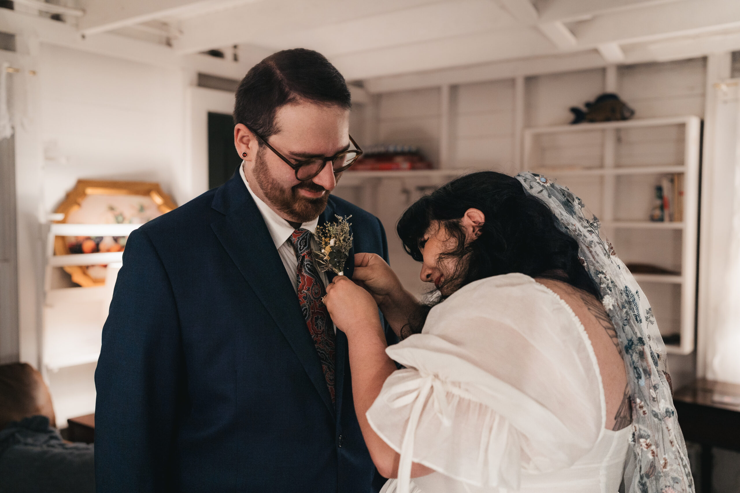 Bride helping groom pin his boutonnière.
