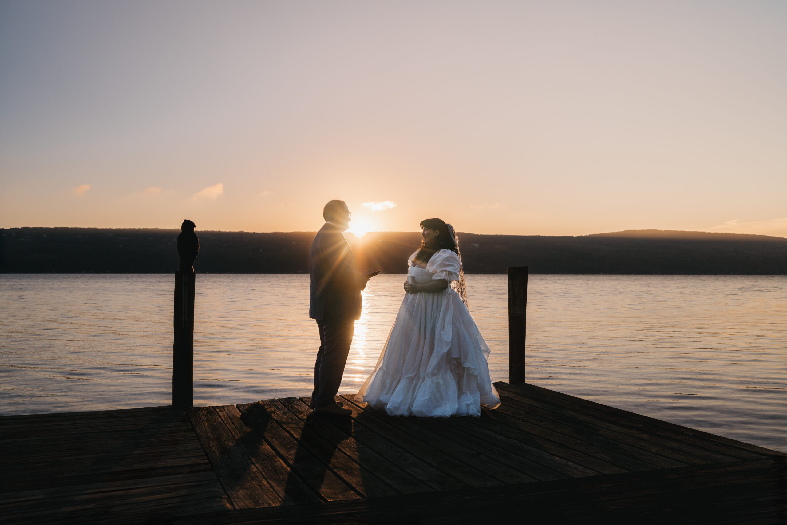 Newlyweds embracing on a dock overlooking Seneca Lake during their Watkins Glen elopement.