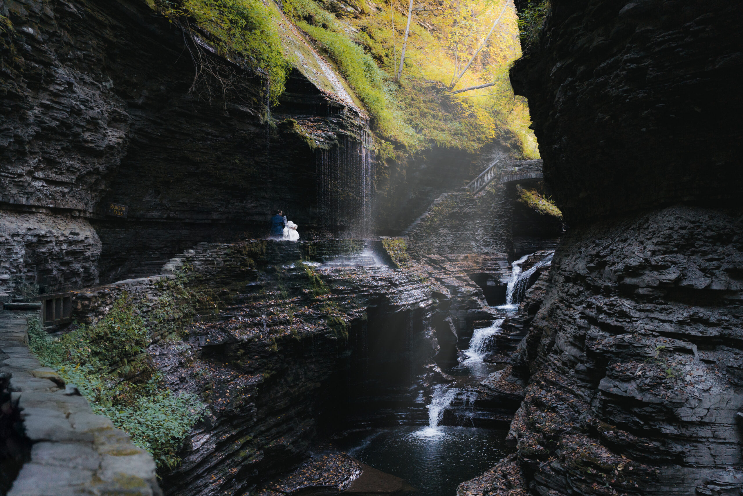 Couple embracing beneath waterfalls during their intimate Watkins Glen elopement.