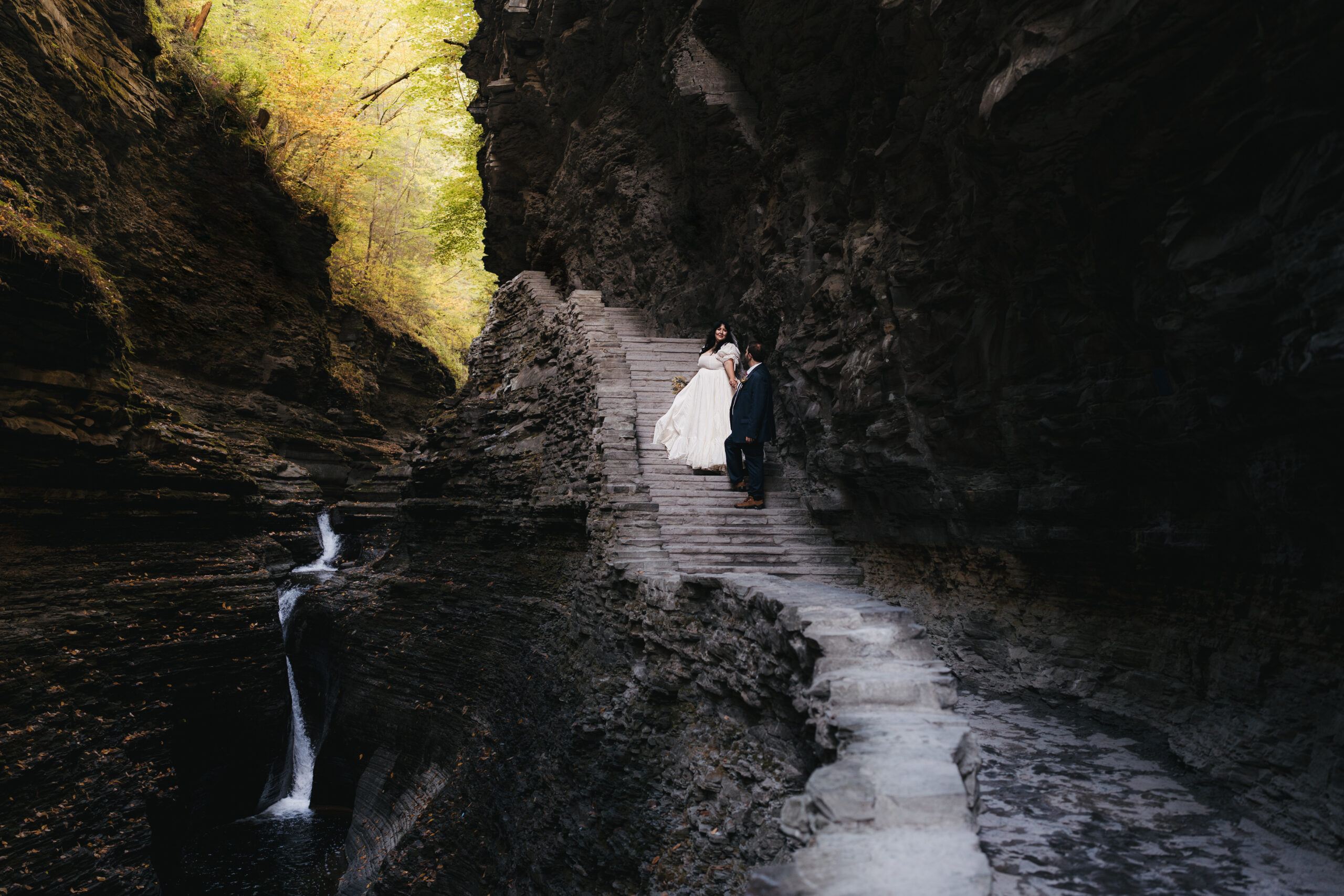 Bride leading groom up stone staircase during their Watkins Glen elopement.