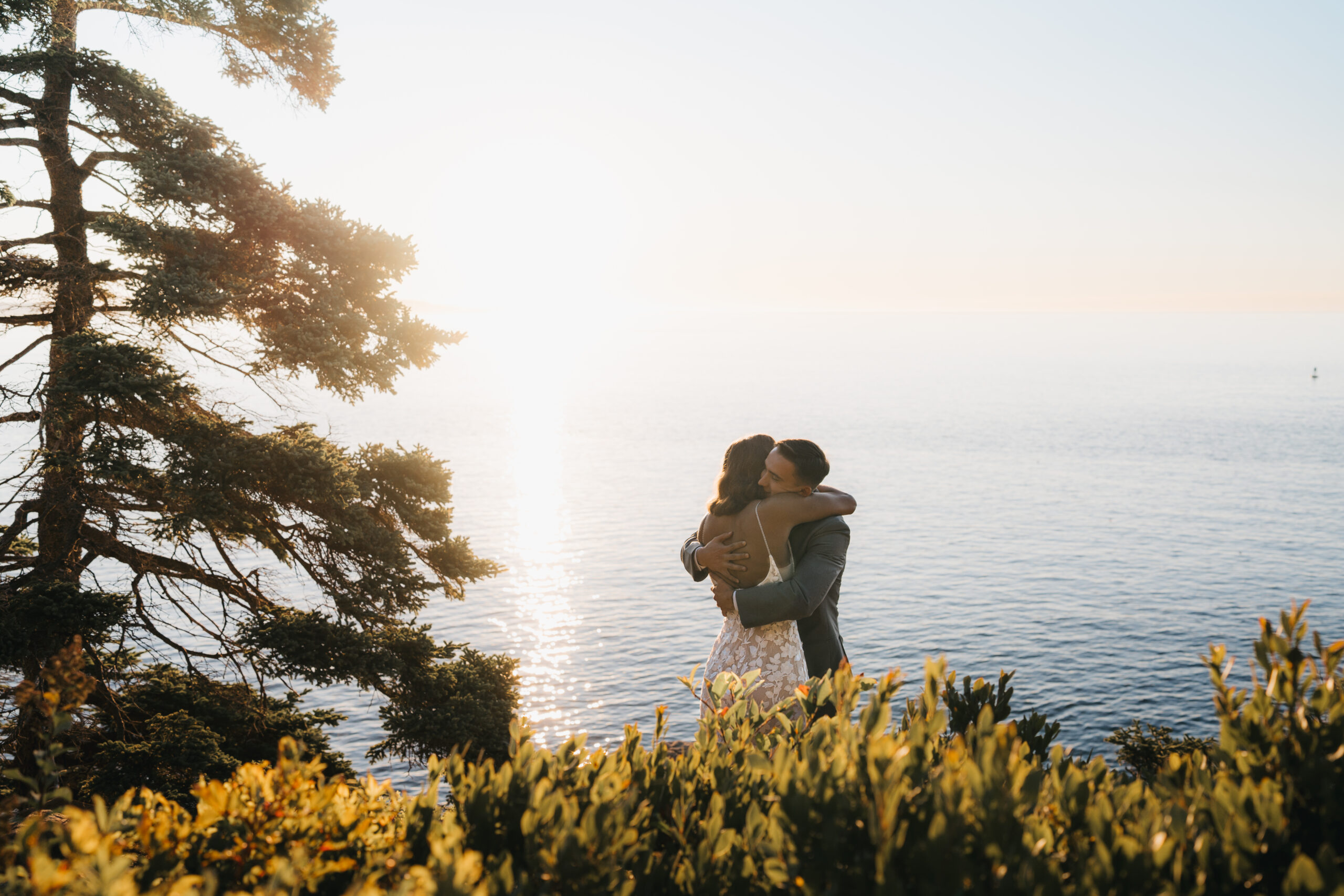 Couple embracing at sunrise overlooking the Atlantic Ocean during a Sunrise Acadia Elopement.