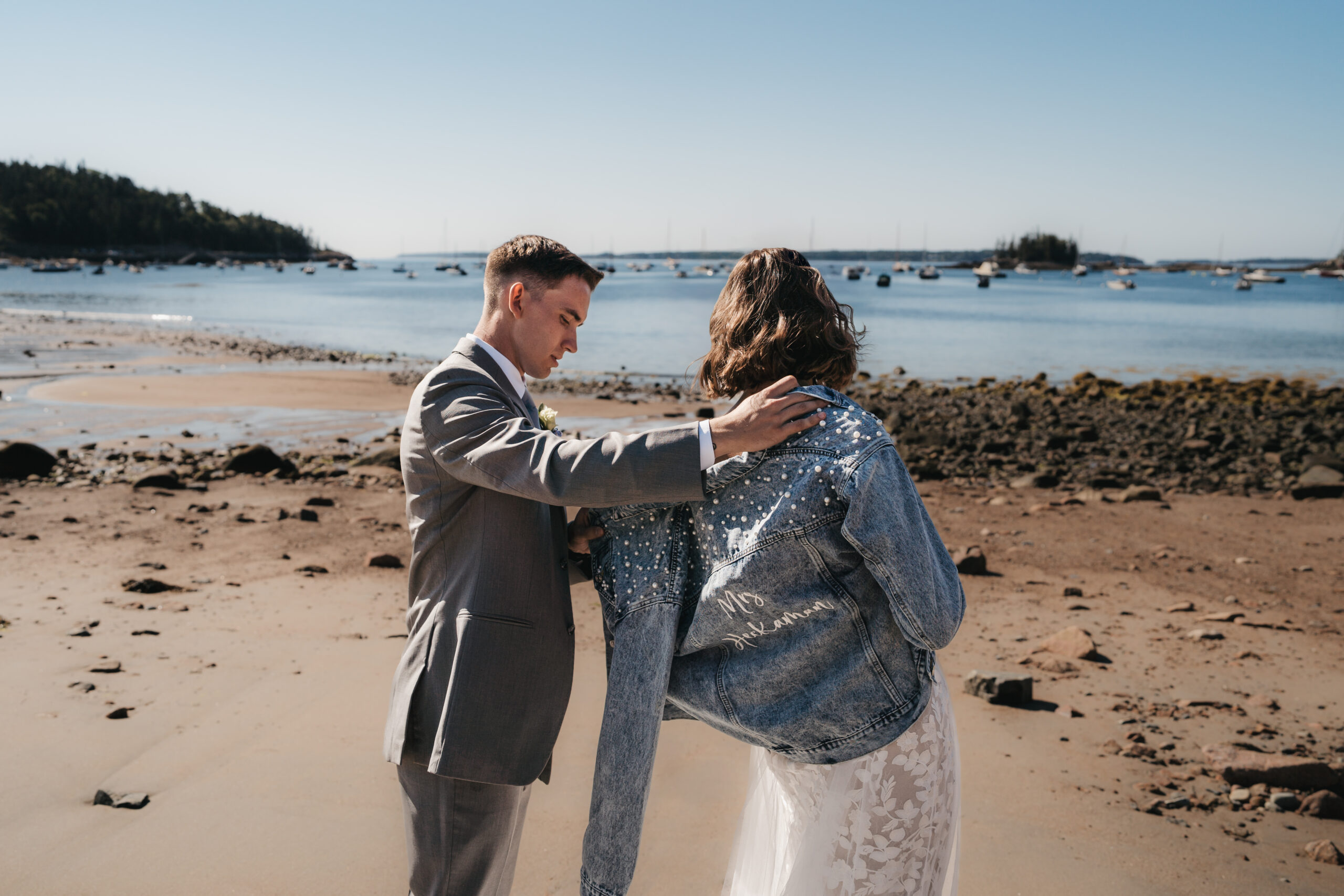 Bride wearing jean jacket at Seal Harbor Beach during a Sunrise Acadia Elopement.