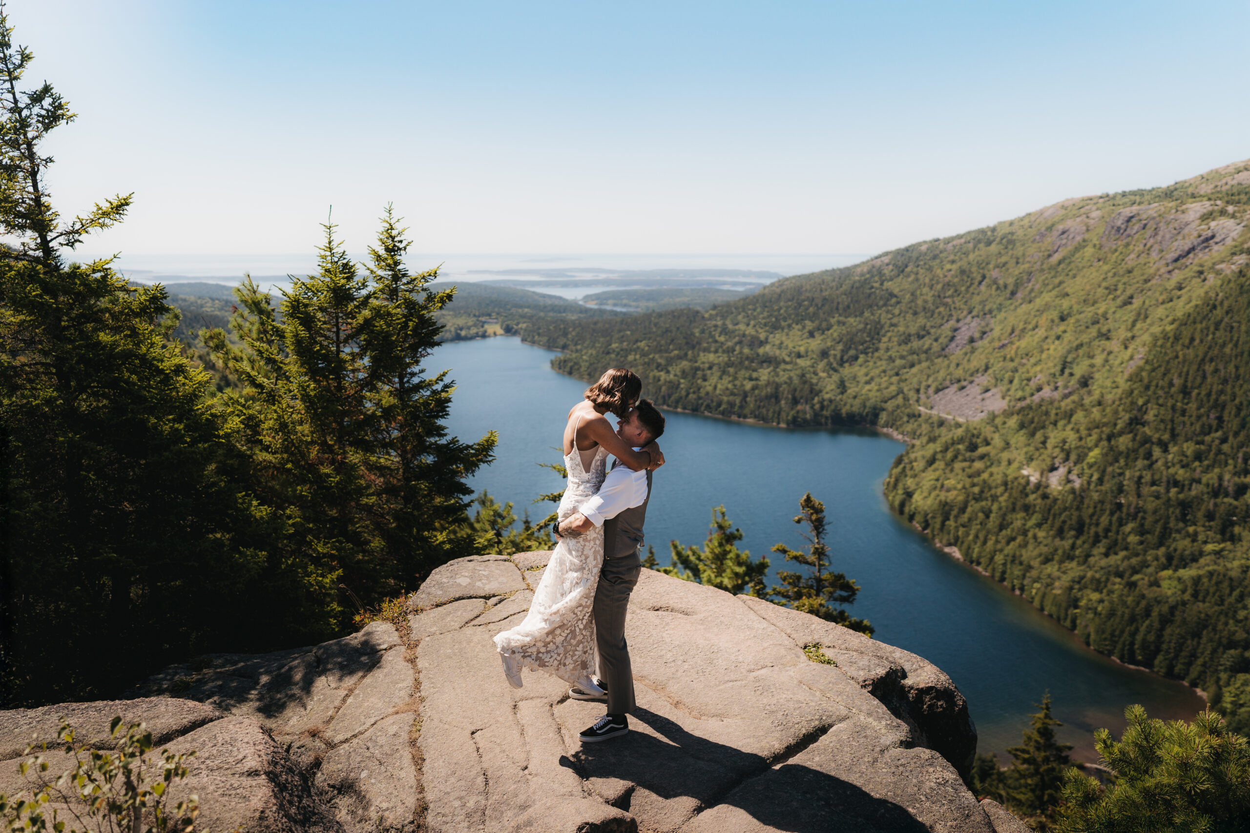 Newlyweds sharing a first kiss at the summit of North Bubble Overlook in Acadia.